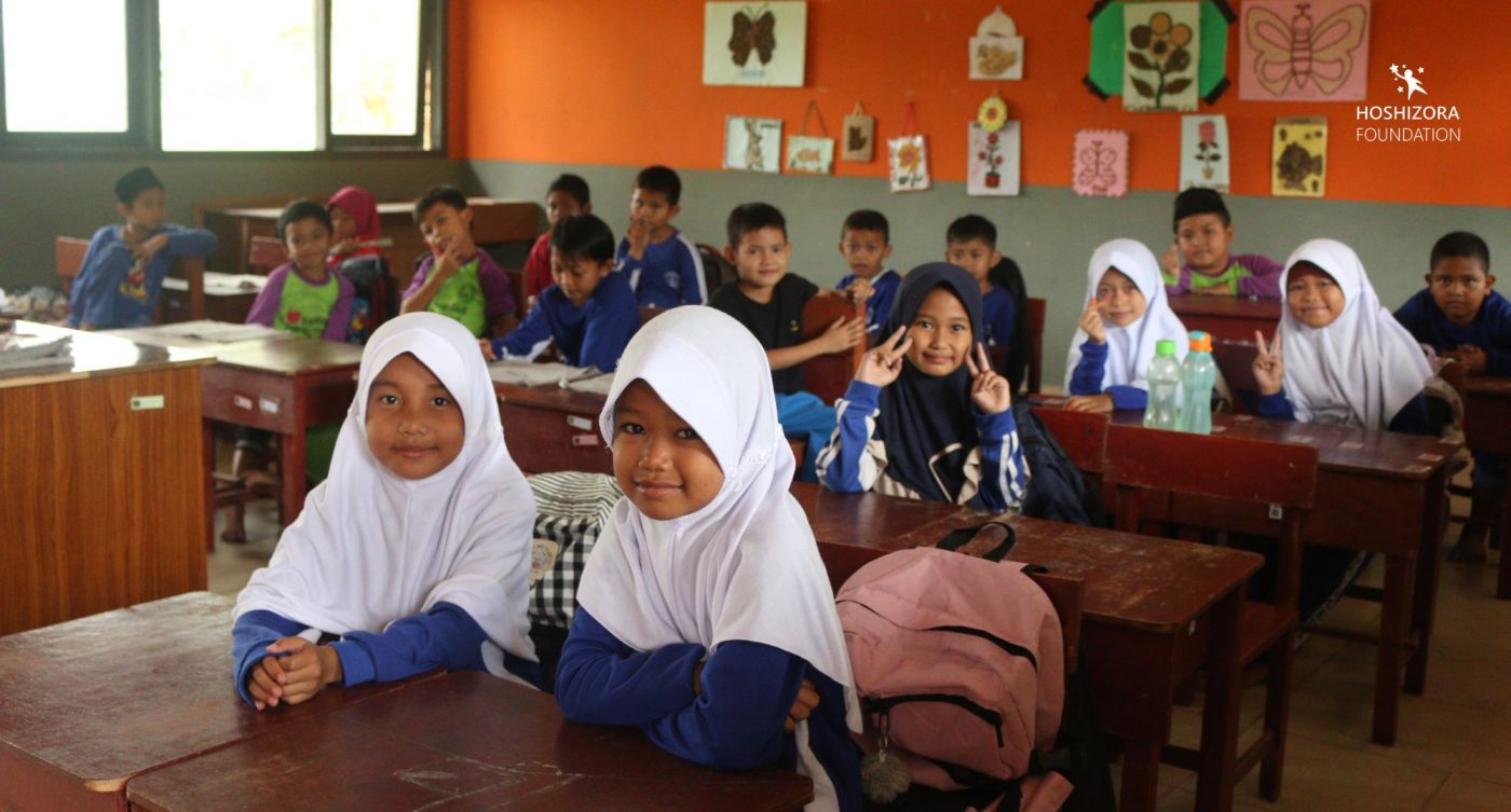 Anak-anak sekolah sedag melihat dan tersenyum ke kamera