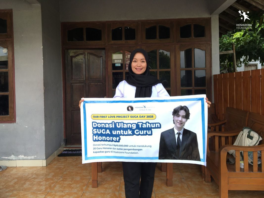 Ibu Bintarti memegang banner sebagai simbolisasi penyerahan donasi dari Fanbase SUGA Indonesia.